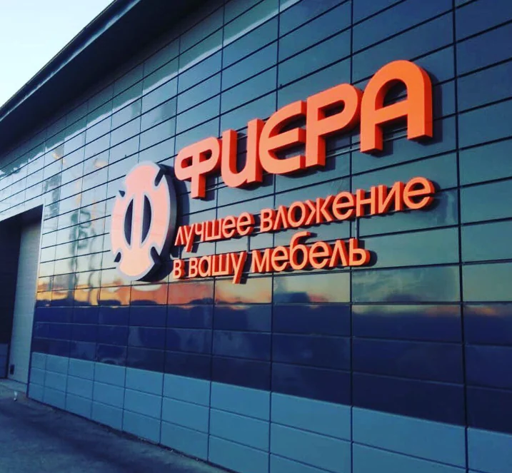 Тёмные кассеты и оранжевая вывеска на фасаде.